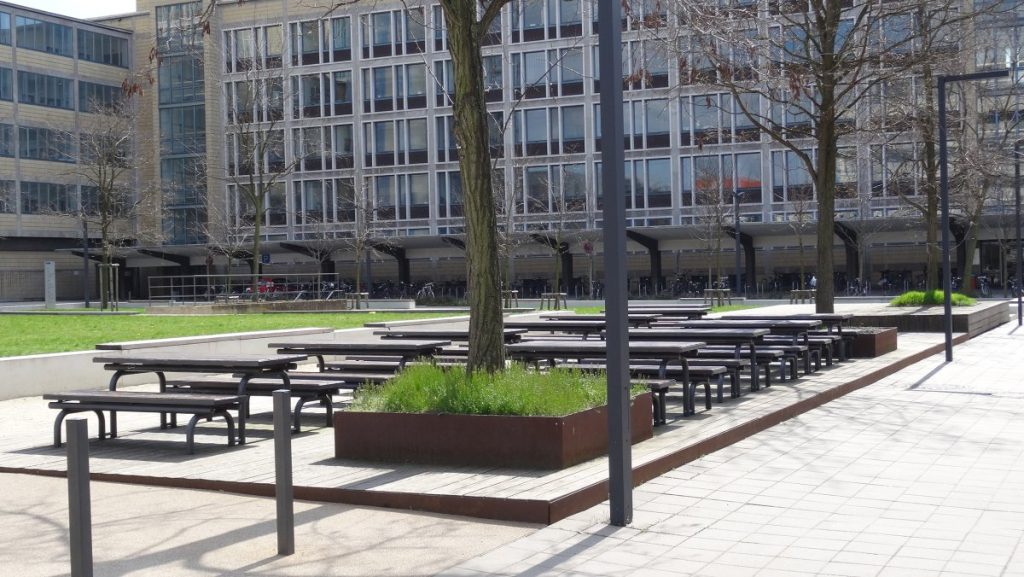 A park featuring benches and trees, situated in front of a building, creating a serene outdoor space.