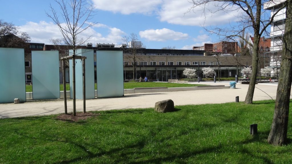 A grassy area featuring several trees and benches for seating, ideal for relaxation and enjoying nature.
