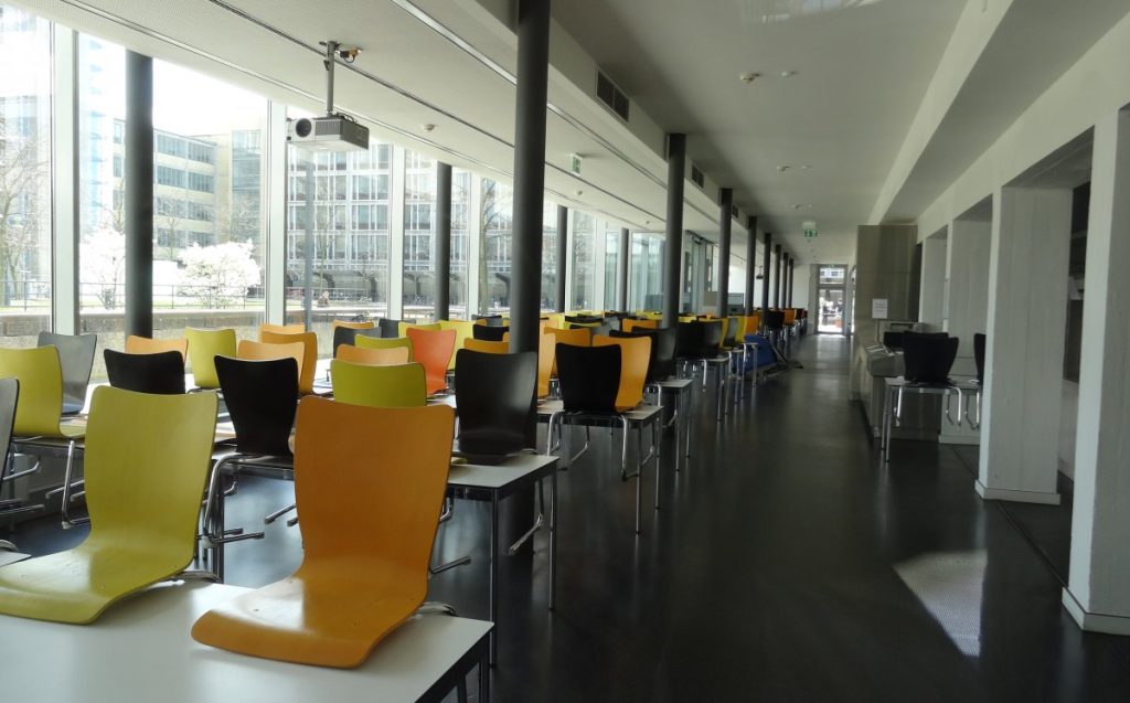  A long dining table surrounded by several chairs, set for a gathering or meeting.
