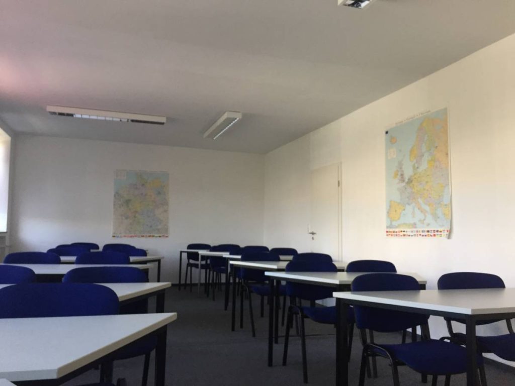 A classroom featuring blue chairs and tables arranged for student seating and learning activities.