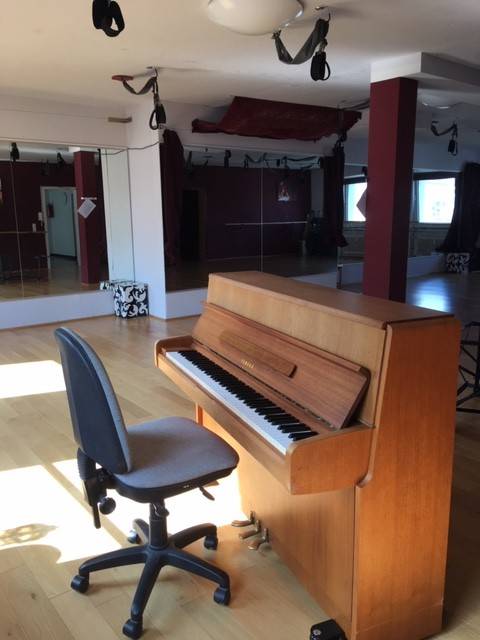  A piano positioned in a room adorned with mirrors and chairs, creating a reflective and elegant atmosphere.
